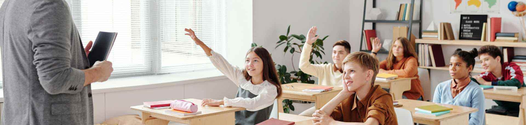 enfants dans une salle de classe levant la main pour répondre à la question de l'instituteur 